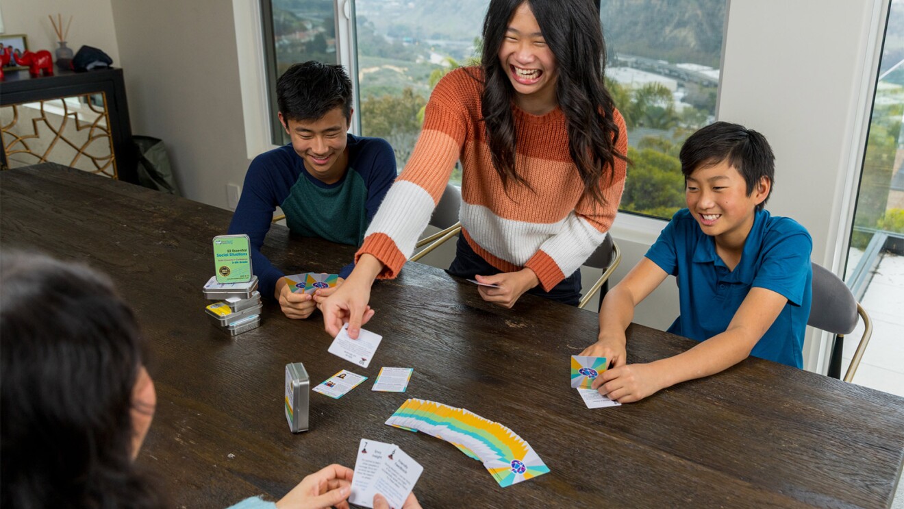 Family enjoying Mind Brain Parenting card deck game together at table with scenic view