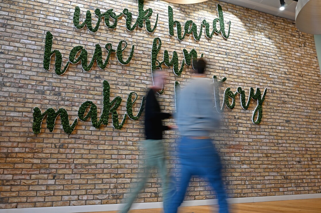 Wall art that says "Work Hard, Have Fun, Make History" with two people walking in front. 