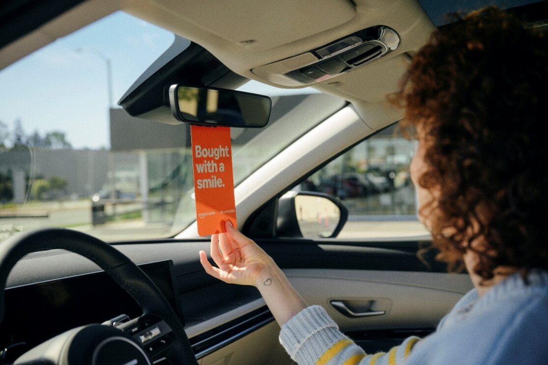 Orange tag with the words "bought with a smile" hanging from rear view mirror