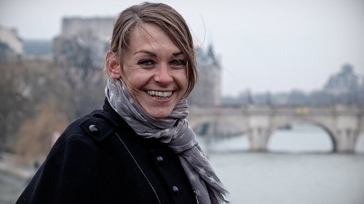 Portrait en buste d'Agnès Martin-Lugand en extérieur devant un pont surplombant une rivière à côté d'un château