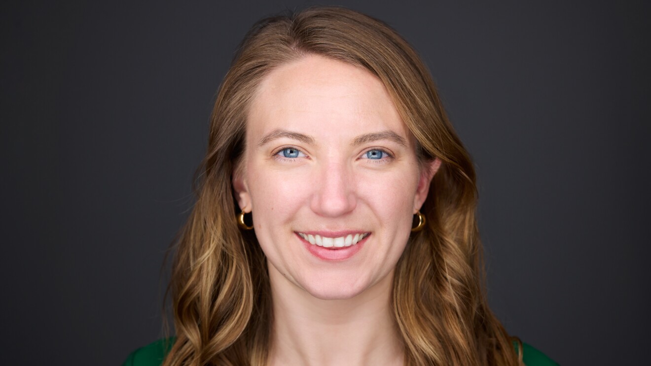 An image of a woman smiling for a headshot photo against a black background.