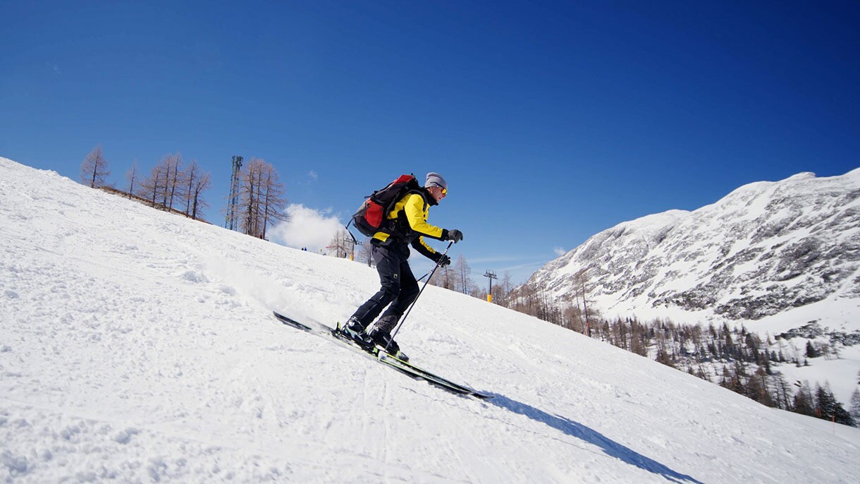 Helmut Edelmaier wears a backpack and skis down the mountain.