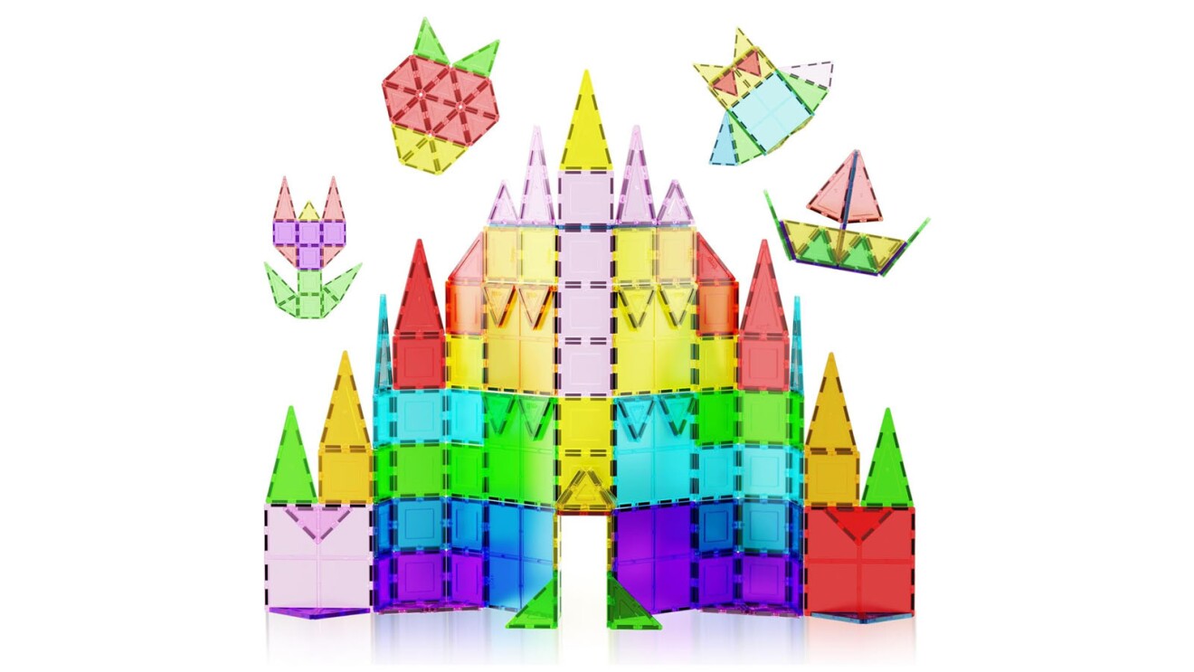 An image of the Picasso Tiles set. There are multiple clear tiles in various colors, stacked to make a castle with smaller figures floating above, including a sail boat, an owl, and a fox.