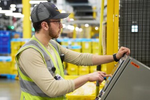 An image of an employee working with a robotic system in an Amazon fulfillment center