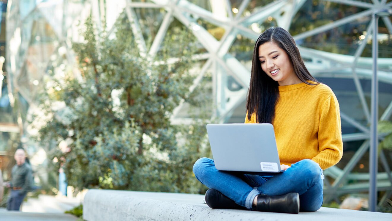 A woman sits outside working on her computer in front of the Amazon Spheres.