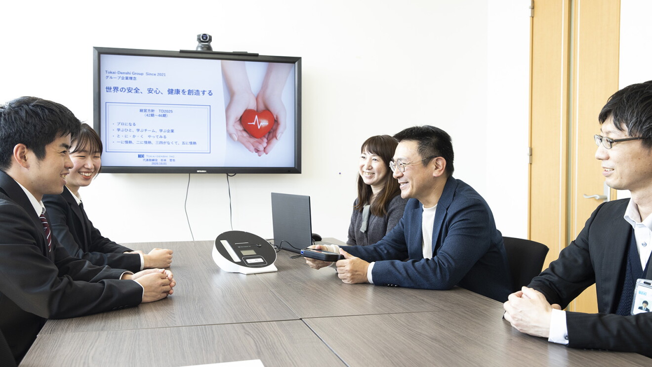 笑顔を見せながら社員をミーティングをしている杉本さん