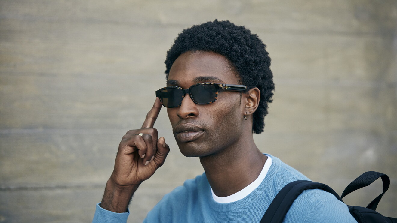 A man wears modern tortoise Echo Frames and activates Alexa with the touch of his finger.