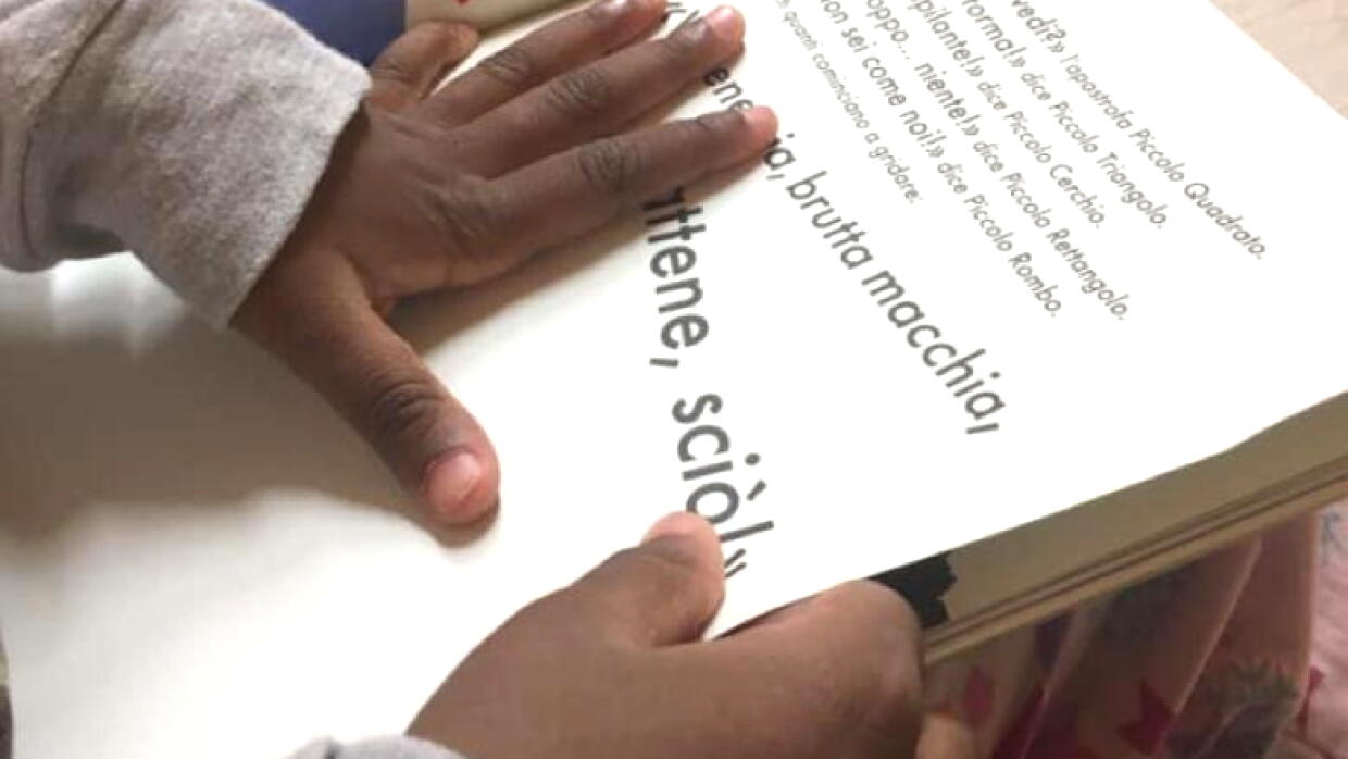 Primo piano delle mani di un bambino che reggono e sfogliano un libro