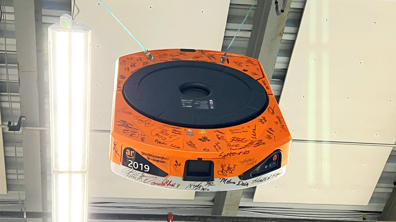 A Hercules robot hangs from the ceiling of a warehouse in tribute of its retirement. It is signed by the employees at the facility.