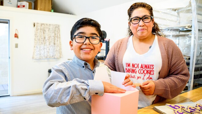 贝克的照片站在她的孩子谁是拿着一个盒子,他折叠饼干的地方。