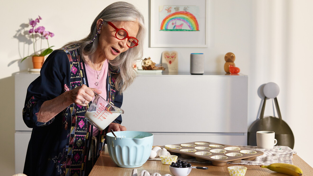 older woman uses her alexa echo device while baking