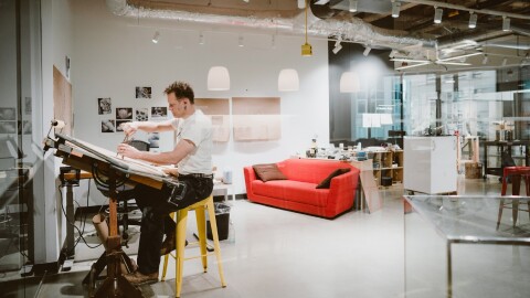 An artist works at a desk in an art studio.