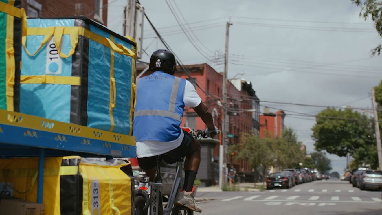 An image of an Amazon employee delivering packages on a bike in New York.