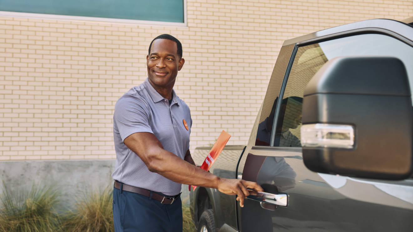 Amazon Autos representative reaches out to open the door on a pick-up truck.