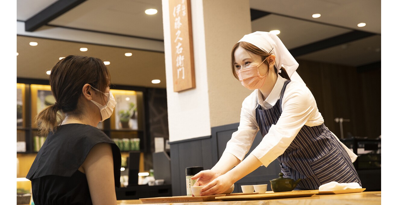 実店舗の席でお茶を出すスタッフ