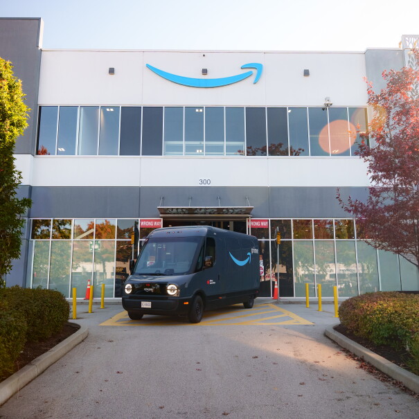 Une image d'une camionnette de livraison Amazon x Rivian devant un entrepôt Amazon