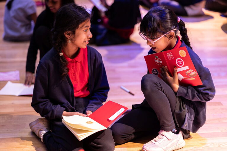Two young girls sitting whilst reading a book