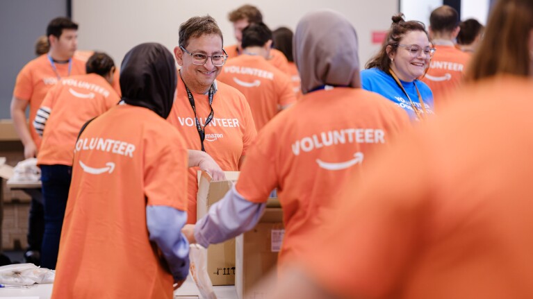 Amazon volunteers in orange shirts helping at community event