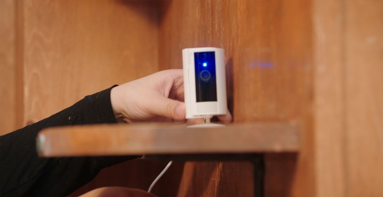 白いセキュリティカメラが木製ラックに置かれている。