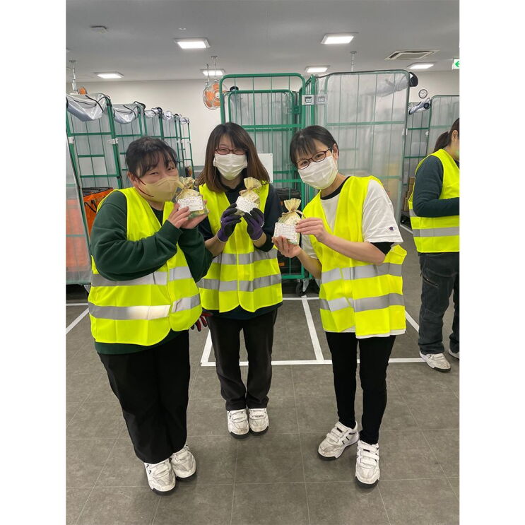 笑顔の3人の女性たちが小さな金色の袋とカードを見せている