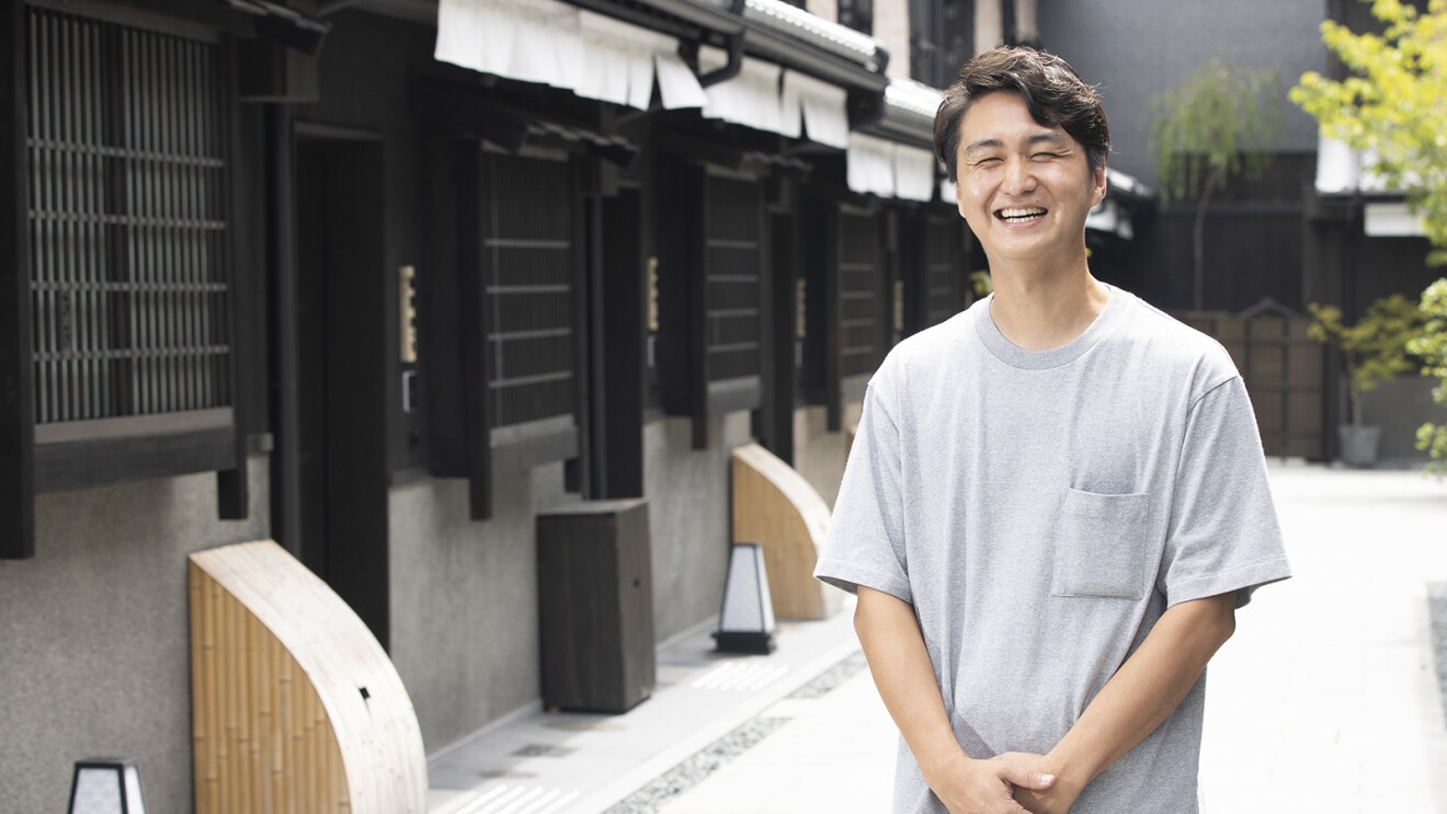 京町家の前に立つ笑顔の男性