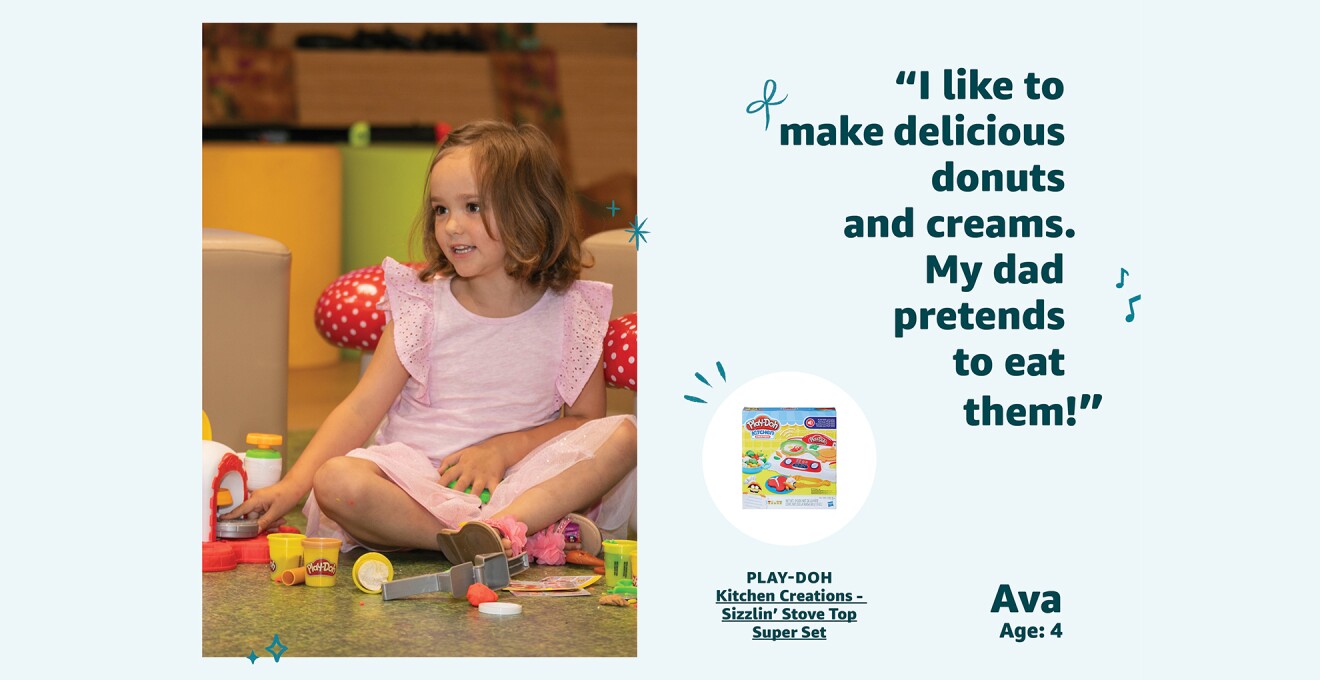 A young girl sits on the floor while playing with a Play-Doh playset