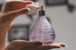 A woman with chipped nail polish squeezes the atomizer on a fragrance bottle.