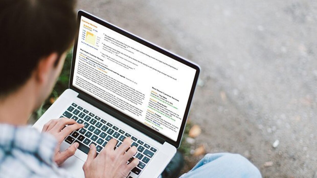 Hombre de espaldas trabajando en un ordenador portátil. Se encuentra en la calle.