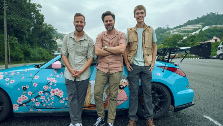 Three men standing by a blue car