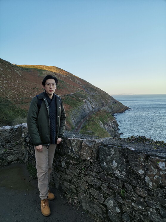 Fangbo Li standing in front of a coastal view