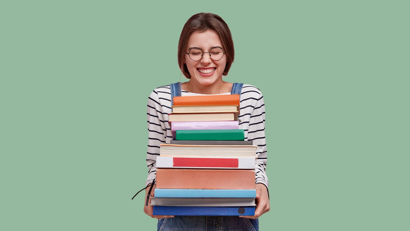 An image of a woman holding a stack of books.