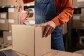 Worker sealing cardboard box with packing tape in warehouse
