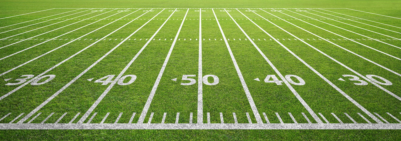 A sideline angle of yard lines are painted on a football field, centered on the 50-yard line.