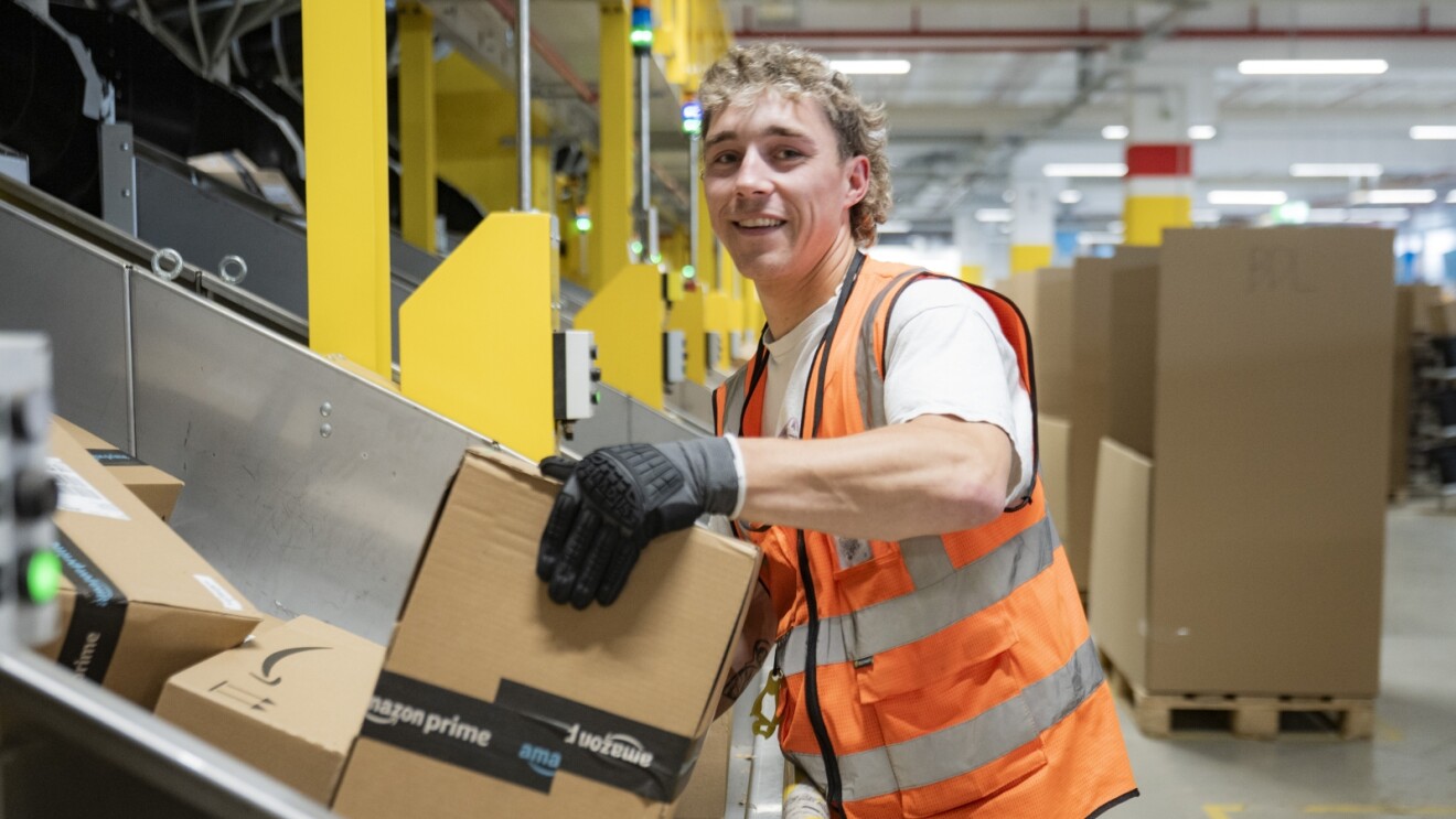 Smiling employee processing packages in Amazon facility