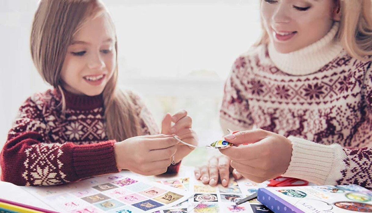 A child and young woman work together on a craft. Images are strewn across the tabletop as part of the craft kit. 
