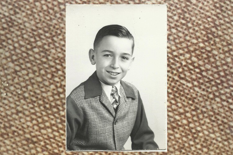 Rick Reefer at age 10. It's a black and white photograph and he is smiling and wearing a tweed jacket.