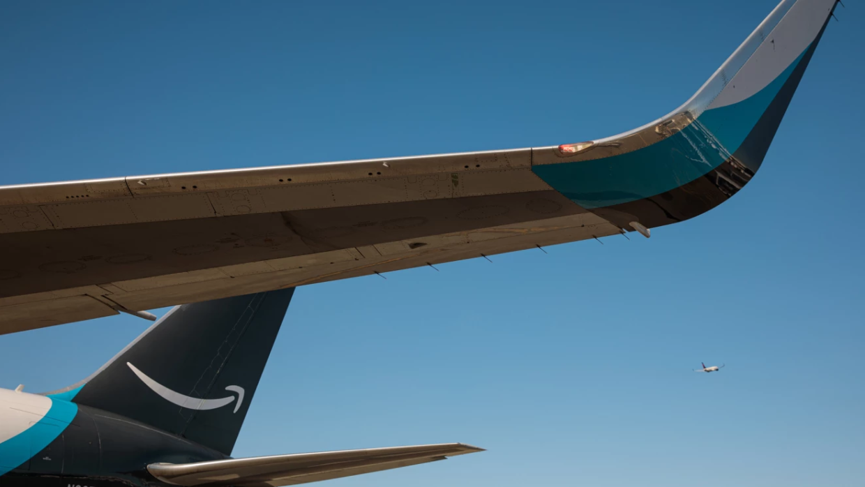 si mostra un'ala e la coda di un aereo amazon air con logo amazon sulla coda