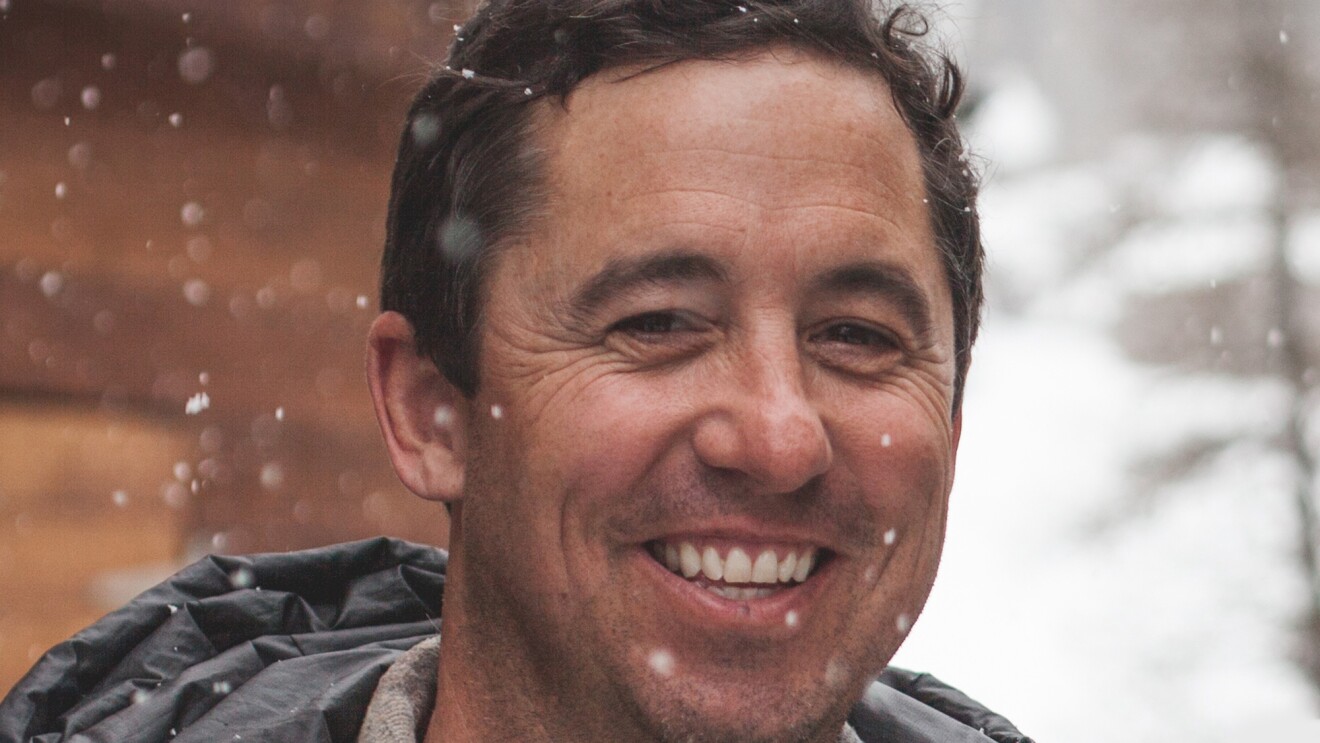 Porter Fox, the Amazon author profiled in this story, is smiling into the camera with falling snow in the background.