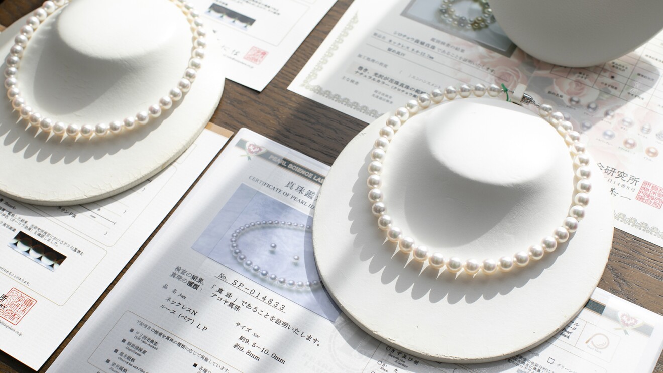 テーブルに置かれたネックレスと、真珠鑑別鑑定書