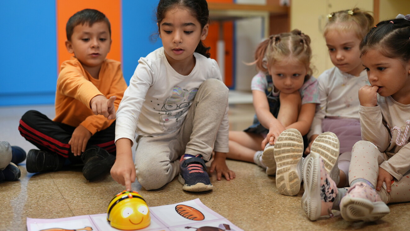 Alumnos de primaria con un robot de lego en el suelo. 