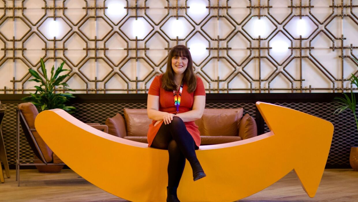 Cheerful employee relaxing on quirky yellow couch shaped as the Amazon smile in office lounge area