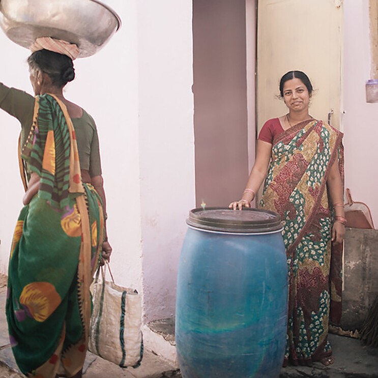 A photo of women standing next to a water jug.