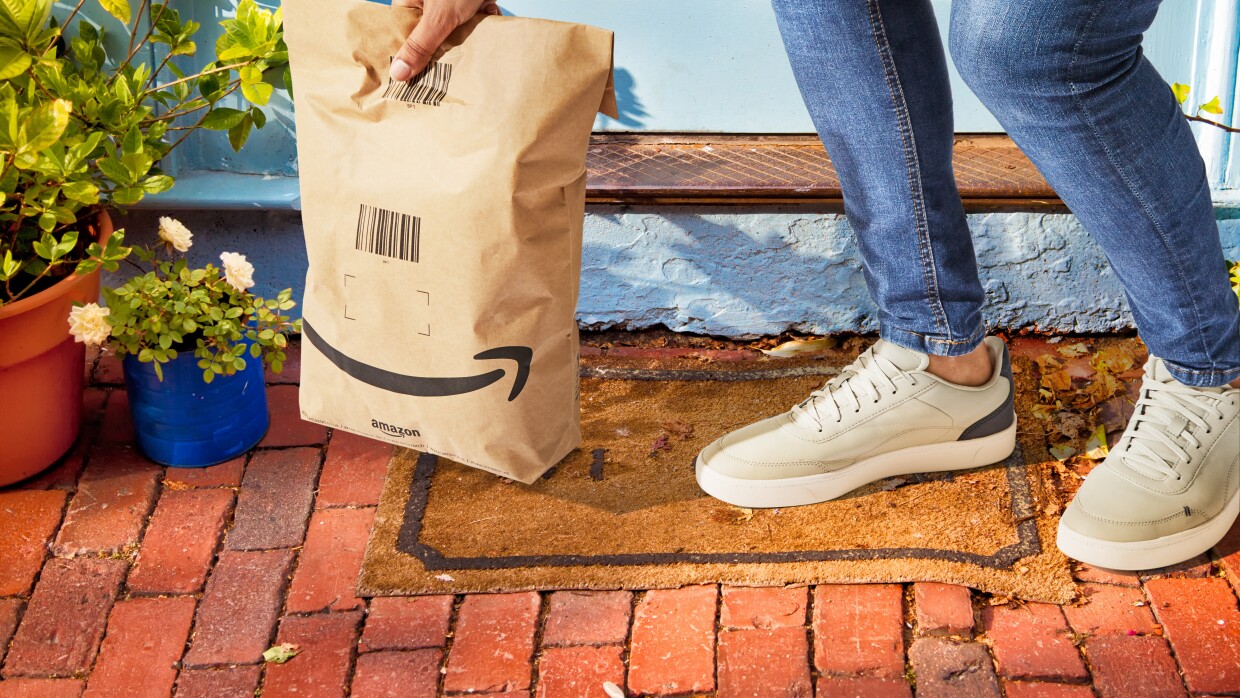 A customer picking up an Amazon delivery in a paper bag with less packaging