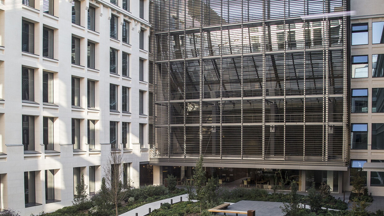 Patio interior de la oficina corporativa en Madrid. El patio es ajardinado y tiene bancos. 