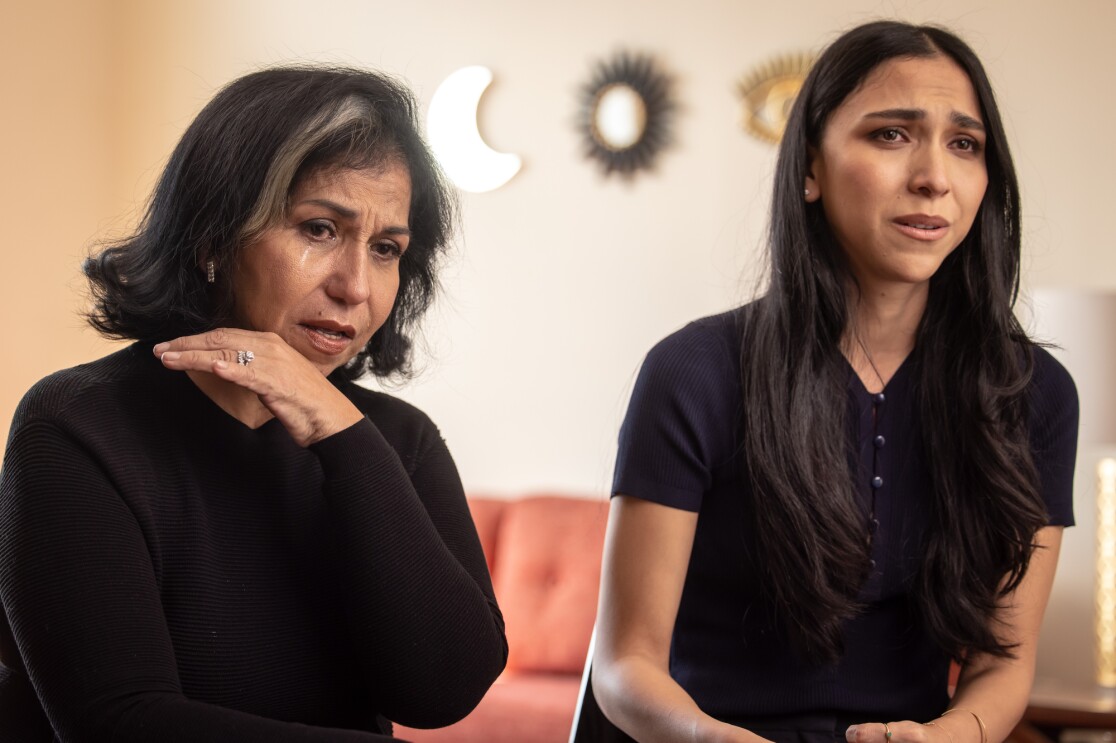 Two women sit side-by-side with emotional looks on their faces.