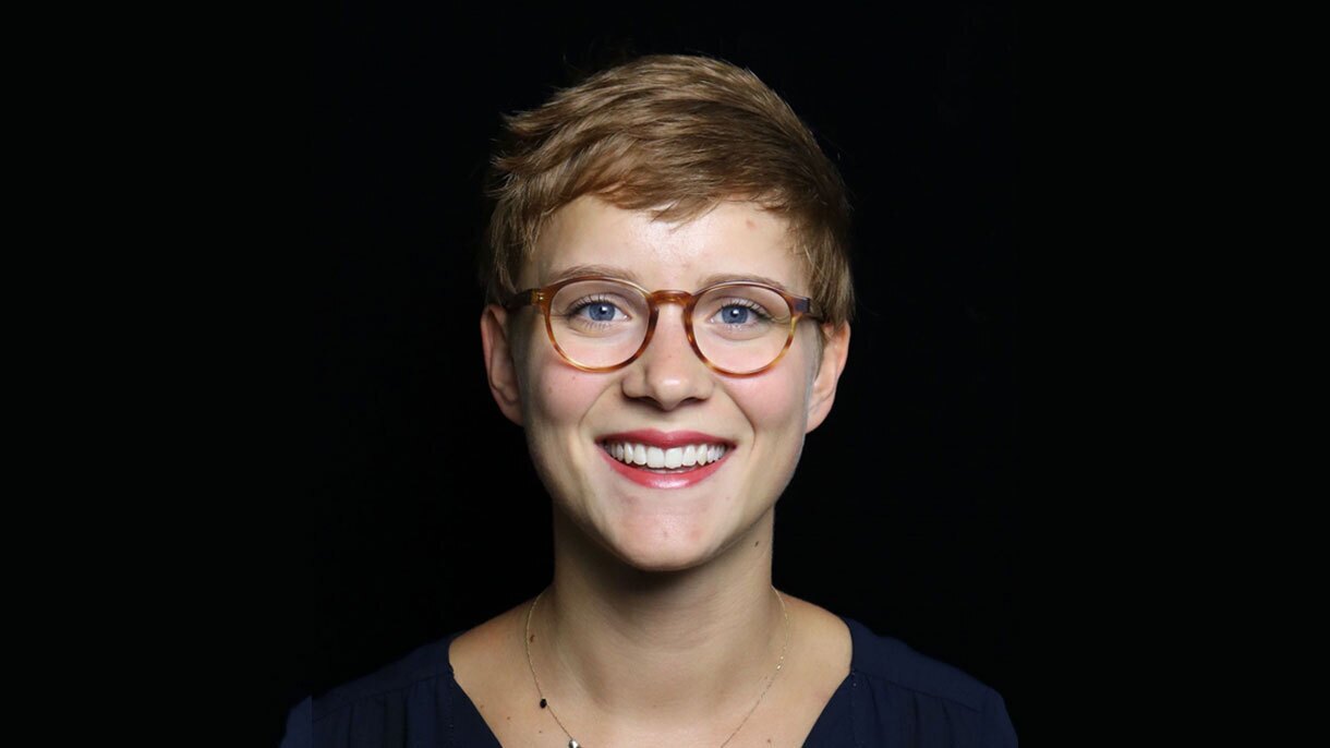 A headshot image of a woman with a black background behind her.