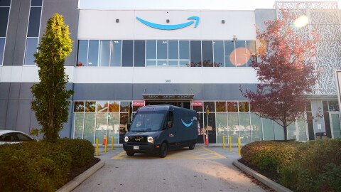 Image of an Amazon x Rivian delivery van parked in front of an Amazon warehouse
