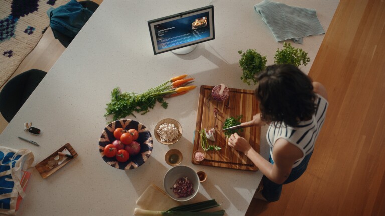 a woman follows a recipe on her echo show while chopping herbs in her kitchen