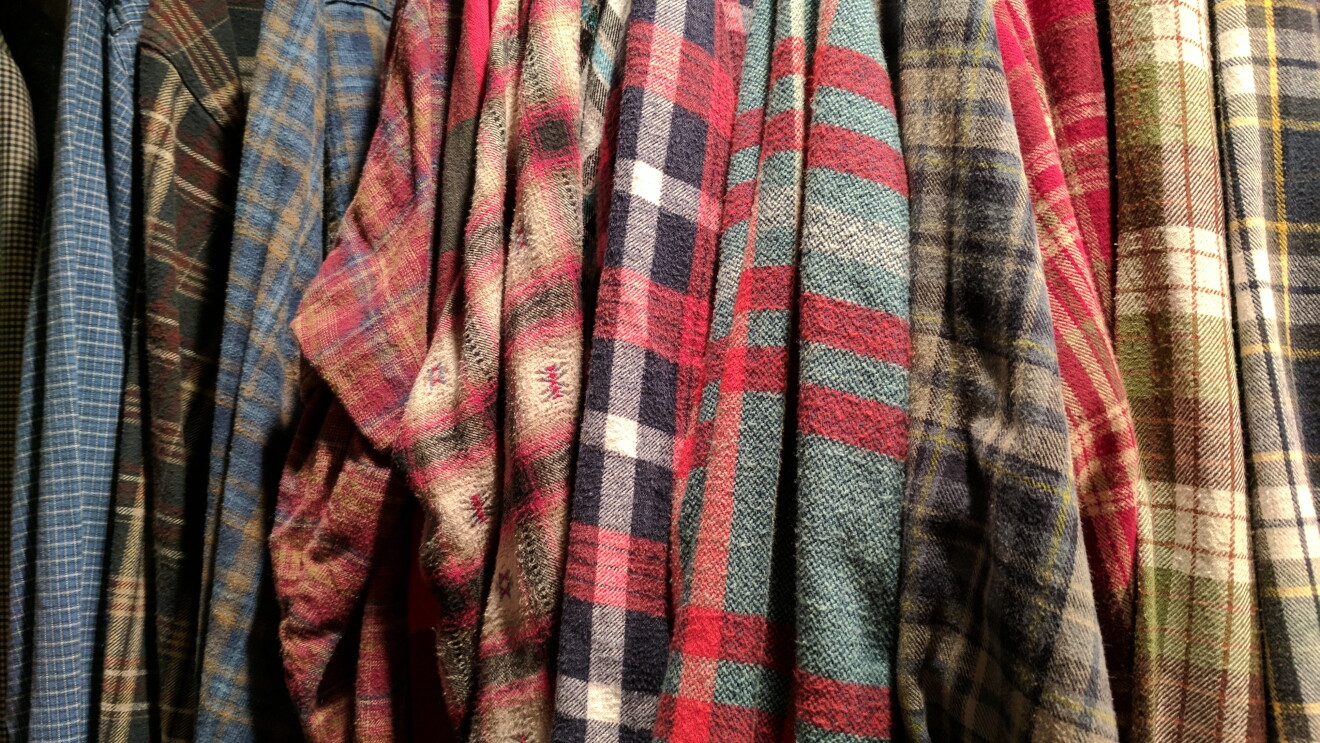 A row of flannel shirts, hanging in a closet