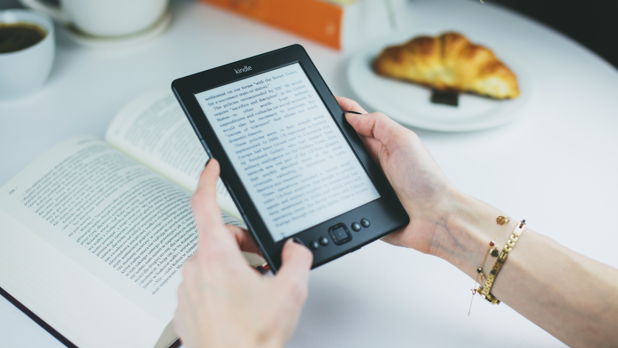 Usuária de Kindle com um livro e um café